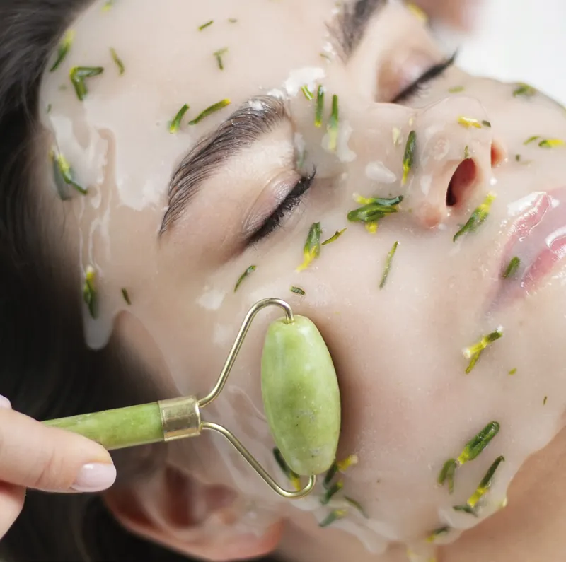 Facial massage with a jade roller over a herbal Hydrojelly® mask