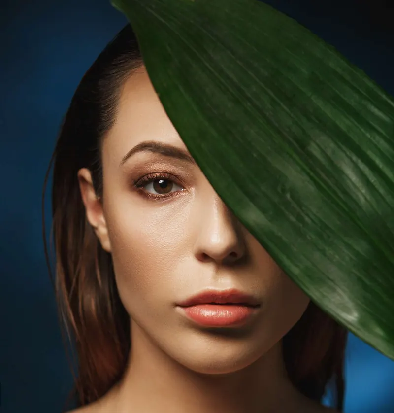 Portret de femeie cu ten luminos, pe jumătate acoperit de o frunză verde — La Fête Chișinău